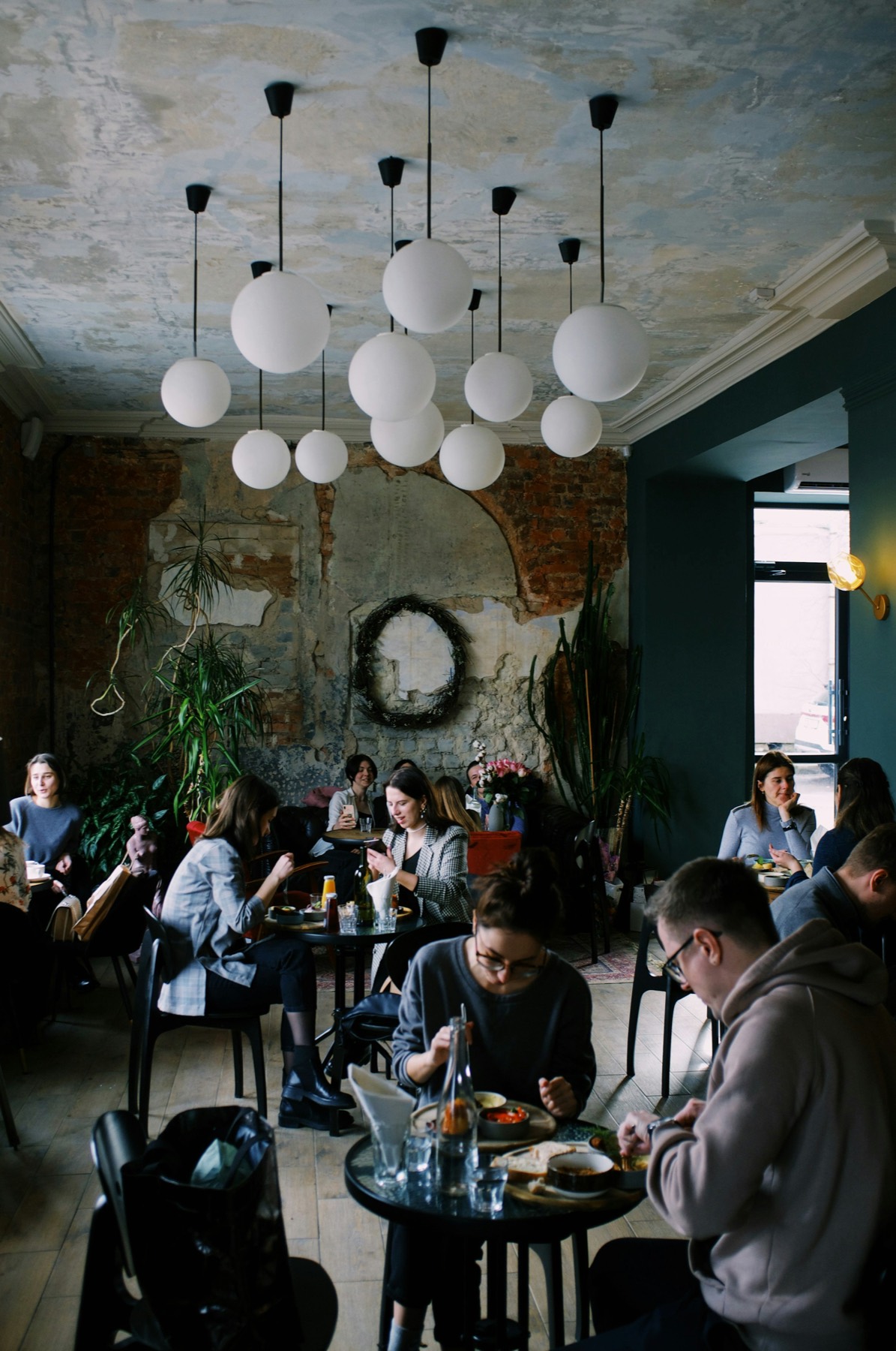 People gathered in conversation around tables in a sunlit room.