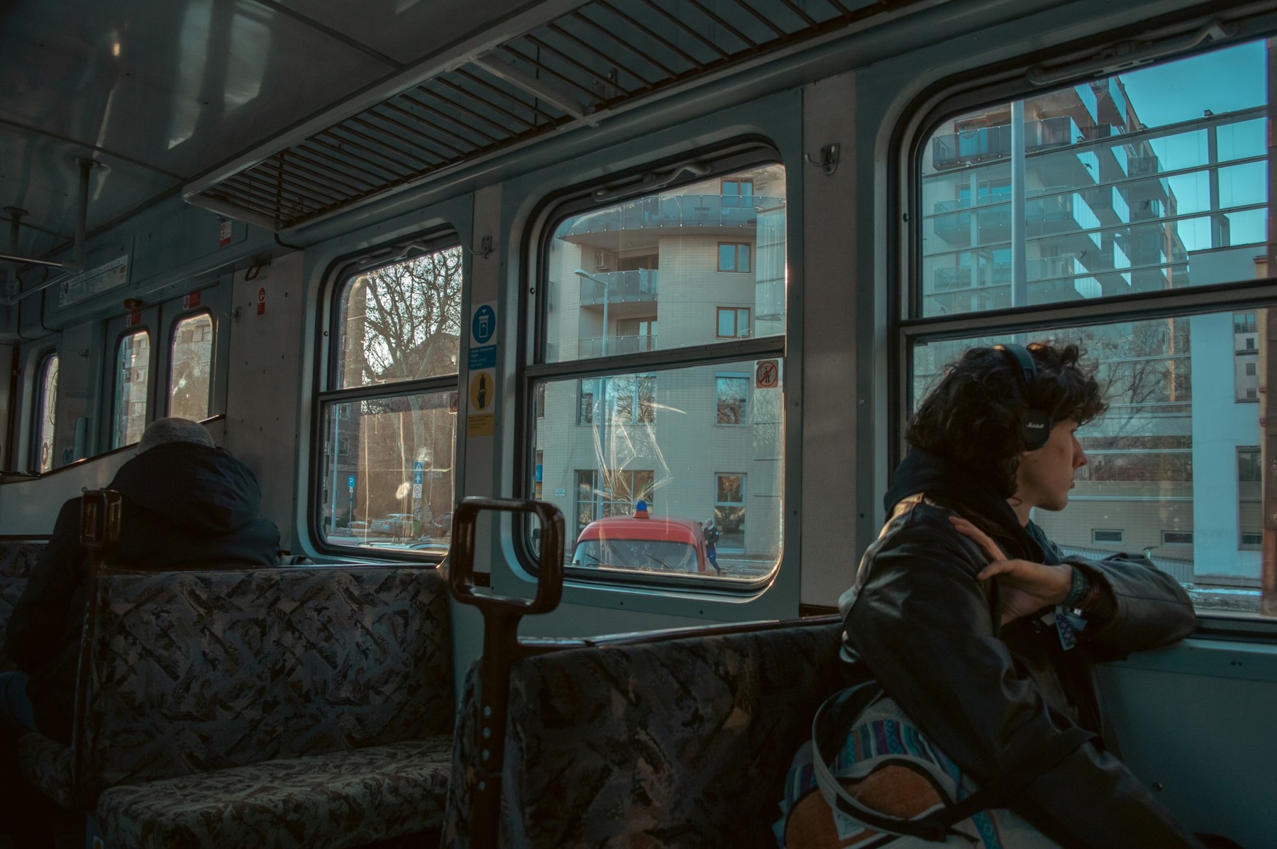 A woman sitting by a train window, watching the city go past.