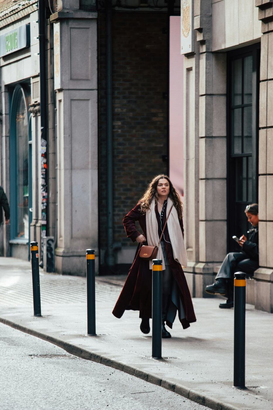 A person in a red coat walking through the city.